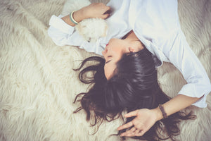 Eine braunhaarige Frau liegt schlafend auf einem Fell. 