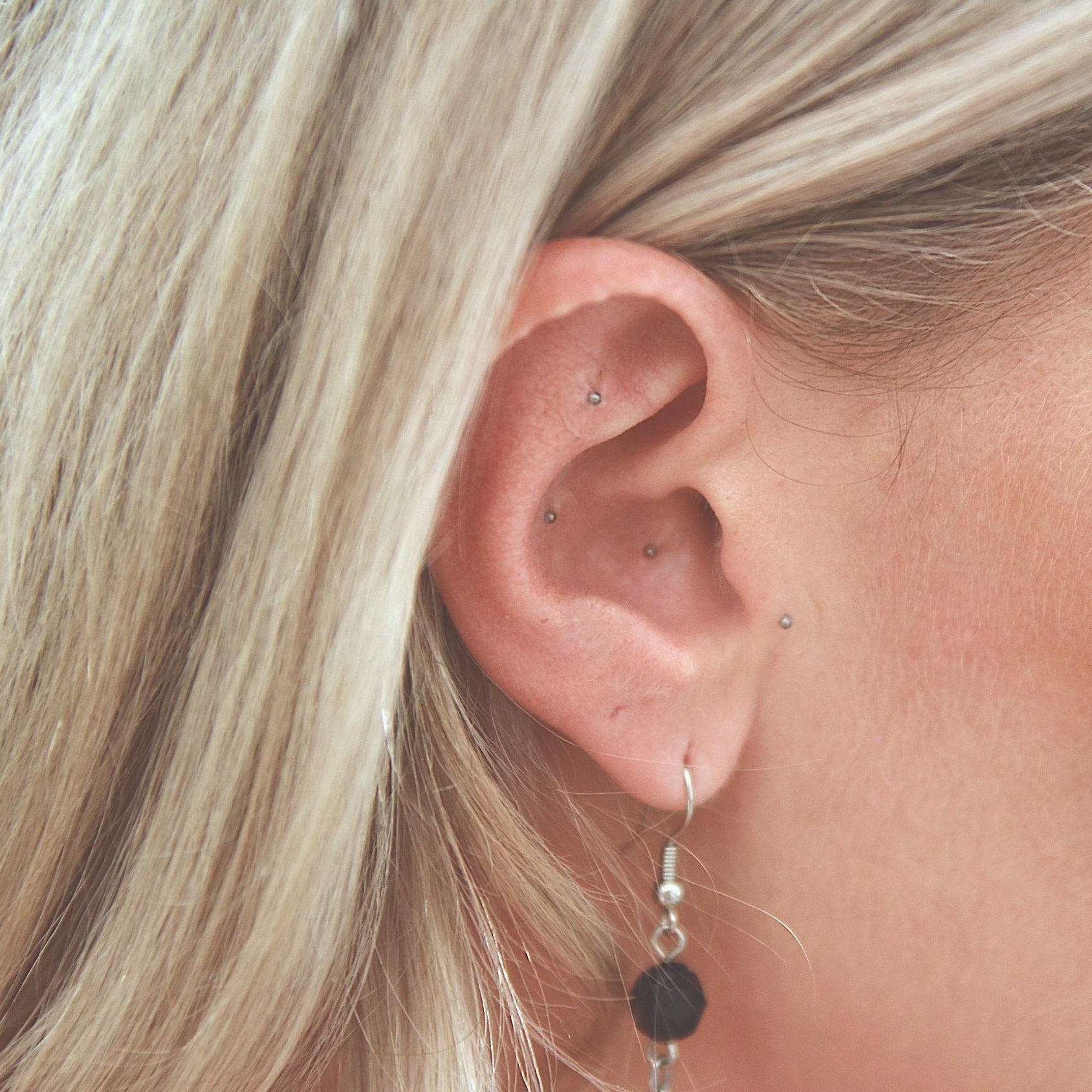 Eine blonde Frau trägt silberne Ear Seeds an ihrem Ohr.